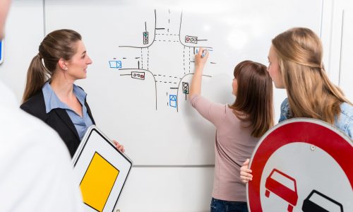 Learner in driving lessons theory explaining traffic situation on white board